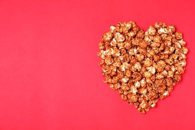 Photo of Heart made of caramel popcorn on color background, top view. Space for text