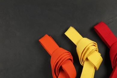 Photo of Colorful karate belts on gray background, flat lay. Space for text