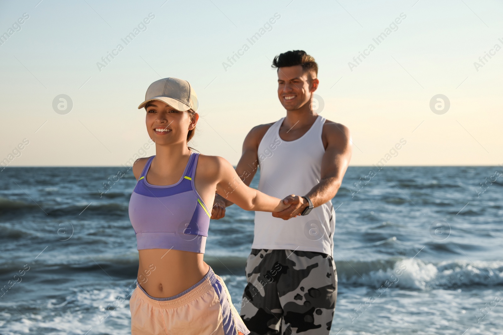 Photo of Sporty couple doing exercise on beach at sunset
