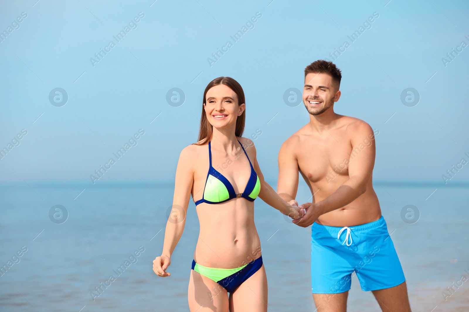 Photo of Young woman in bikini with her boyfriend on beach, space for text. Lovely couple