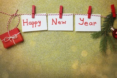 Photo of Happy New Year greeting card. Paper notes with words and decor on shiny background, flat lay