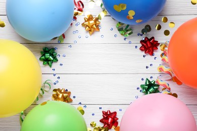 Photo of Flat lay composition with balloons and confetti on white wooden table, space for text. Birthday celebration