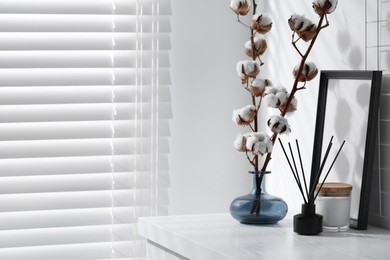 Photo of Reed diffuser, candle and cotton branches with fluffy flowers on white wooden table indoors. Space for text