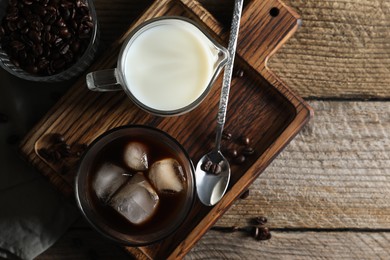 Photo of Delicious iced coffee, milk and beans on wooden table, flat lay