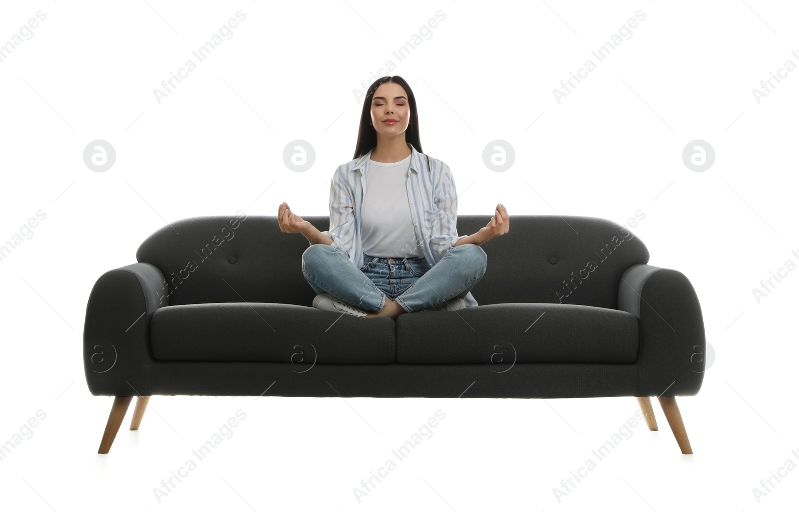 Photo of Young woman meditating on comfortable grey sofa against white background