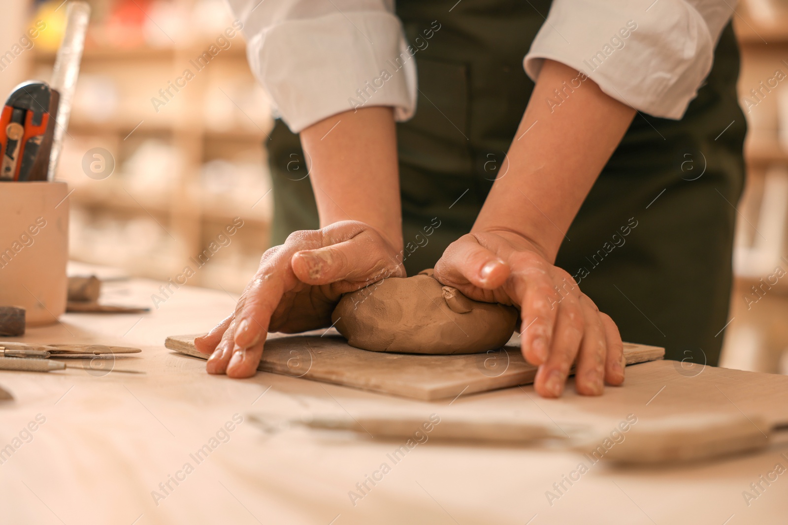 Photo of Woman crafting with clay at table indoors, closeup