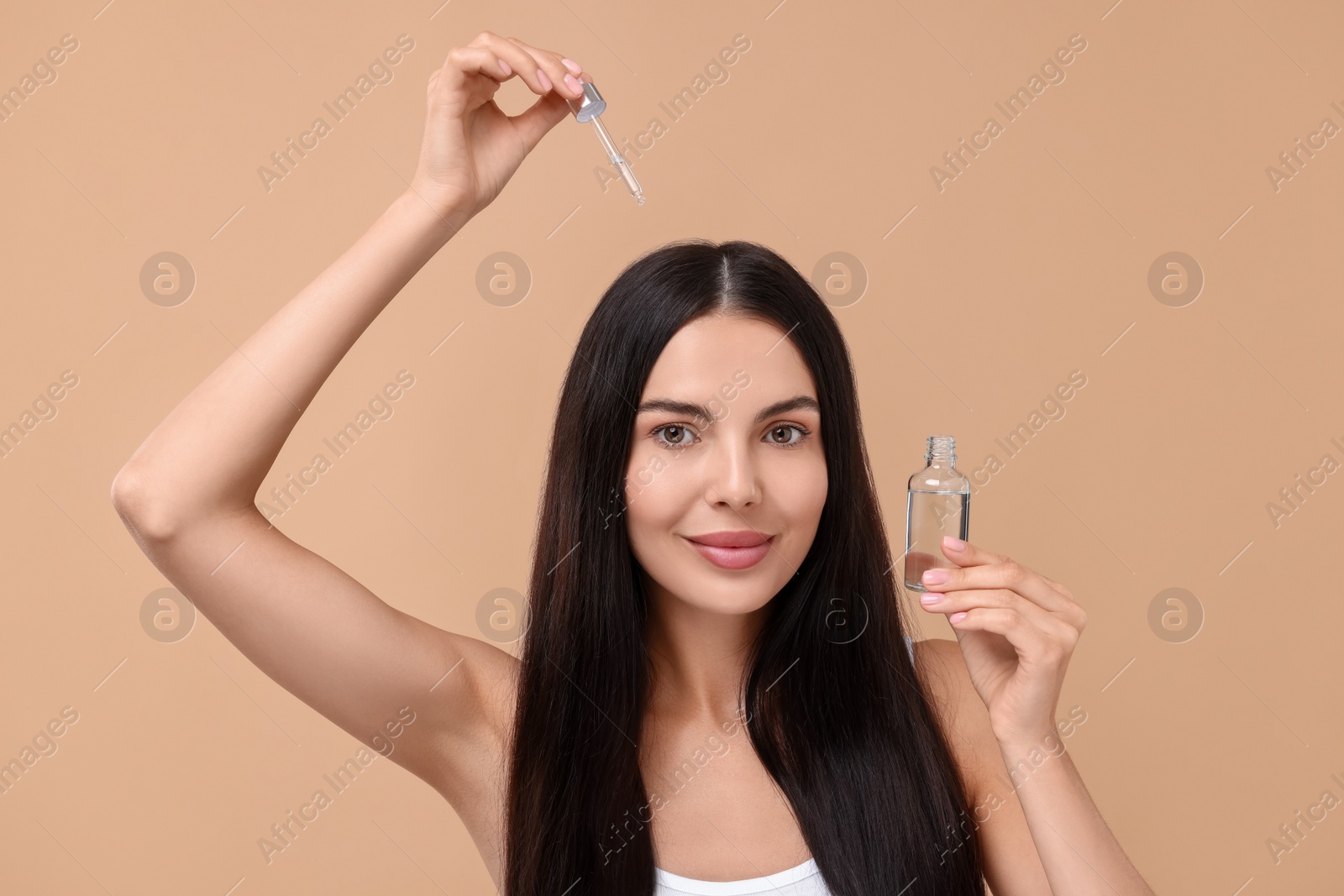 Photo of Beautiful woman applying hair serum on beige background. Cosmetic product