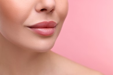 Woman with beautiful lips on pink background, closeup. Space for text