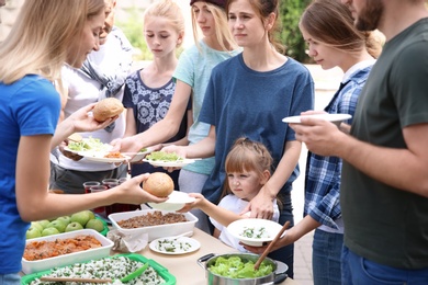 Volunteers serving food for poor people outdoors