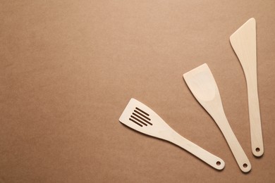 Photo of Different wooden spatulas on brown background, flat lay. Space for text