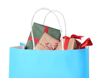 Light blue paper shopping bag full of gift boxes on white background
