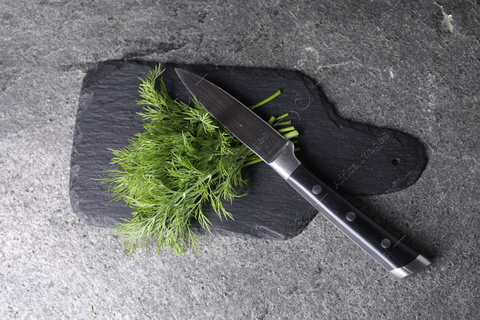 Photo of Sprigs of fresh green dill and knife on grey table, top view