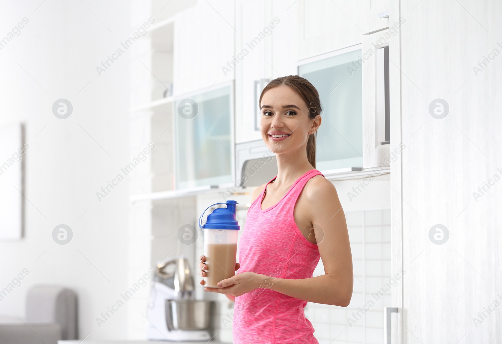 Photo of Athletic young woman with protein shake in kitchen