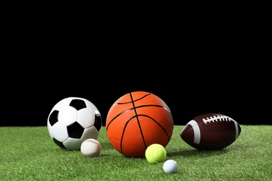 Photo of Many different sports balls on green grass against black background, space for text