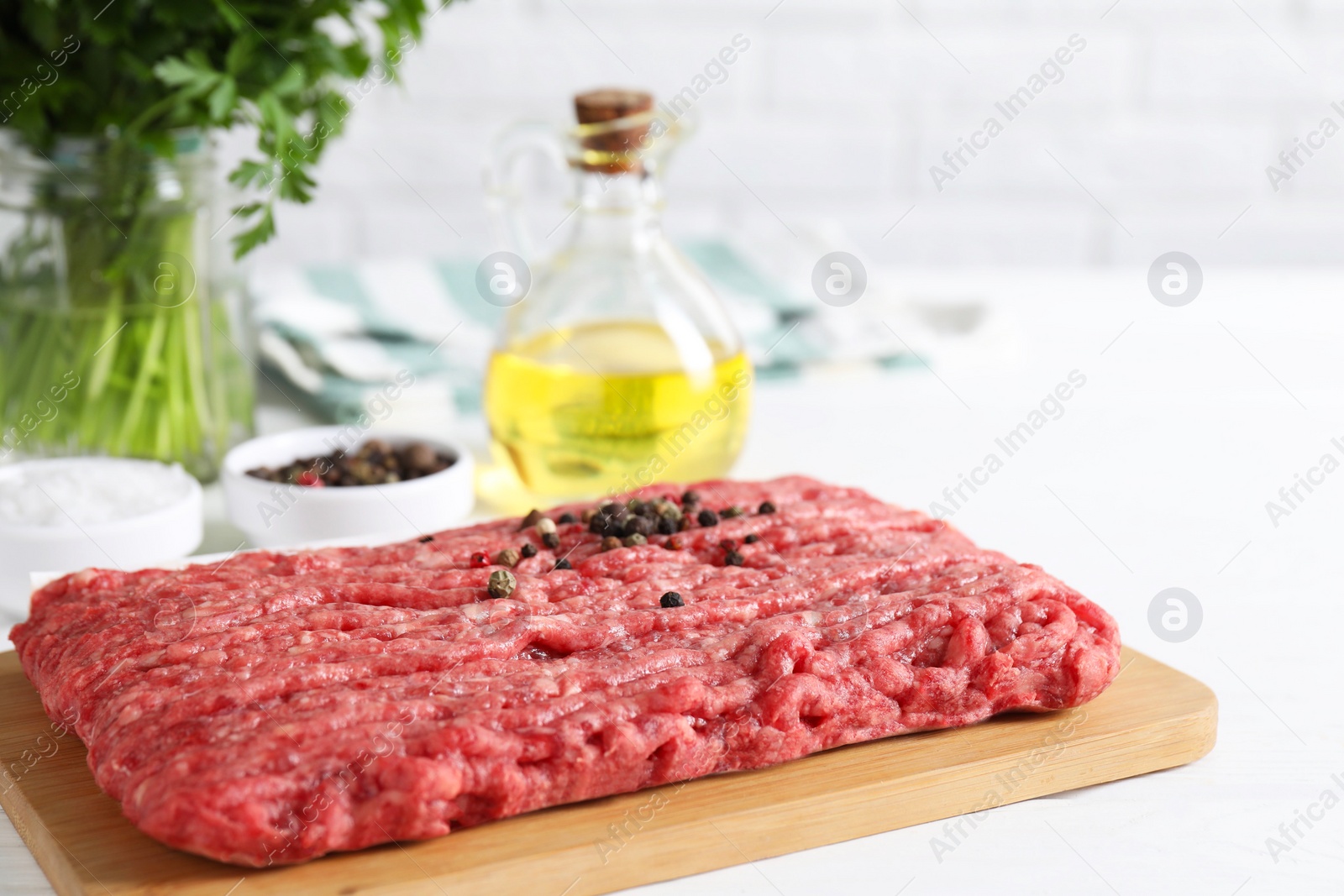 Photo of Raw ground meat, spices, oil and parsley on white table