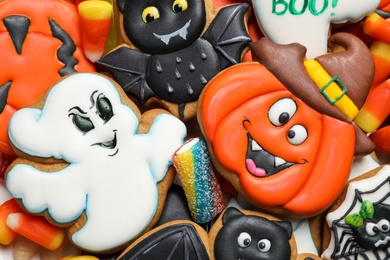 Top view of tasty cookies and sweets for Halloween party as background, closeup