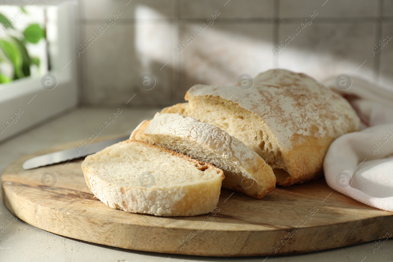 Photo of Freshly baked sourdough bread and knife on light table indoors