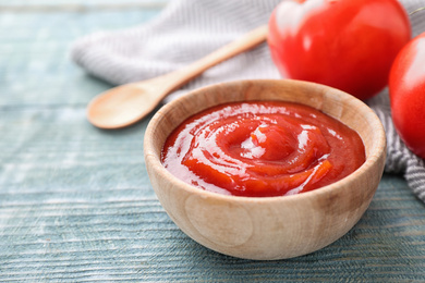 Photo of Tasty tomato sauce on blue wooden table, closeup