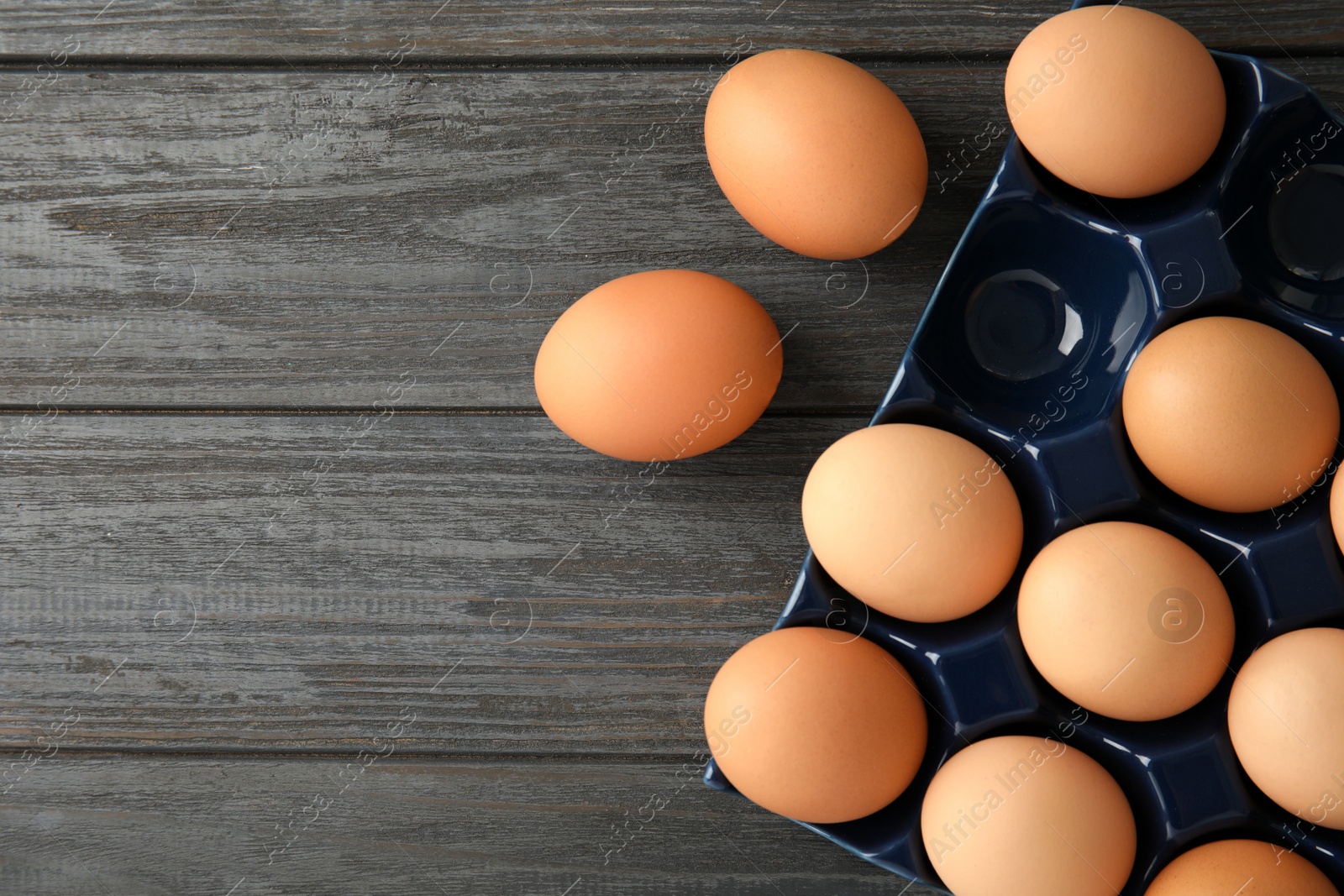 Photo of Raw chicken eggs in ceramic holder on wooden background, top view. Space for text