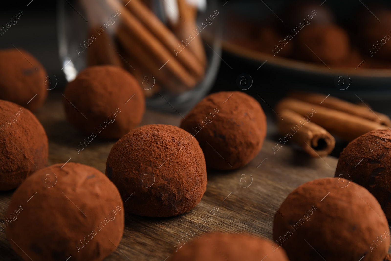 Photo of Delicious chocolate truffles powdered with cocoa on wooden board, closeup