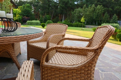 Rattan armchairs and table at backyard near beautiful garden