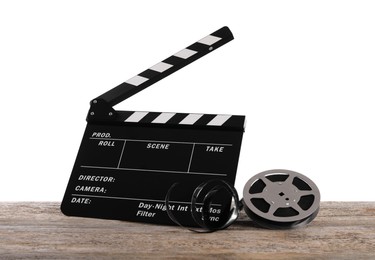 Photo of Movie clapper and film reel on wooden table against white background