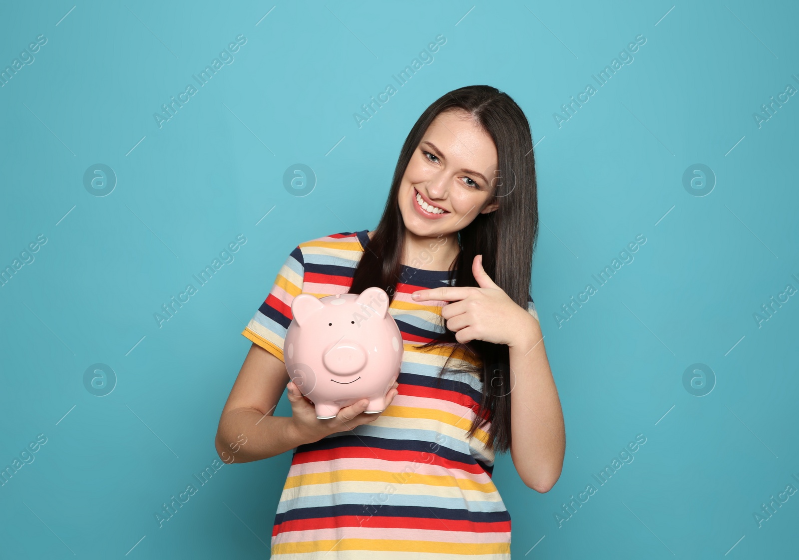 Photo of Young woman with piggy bank on color background