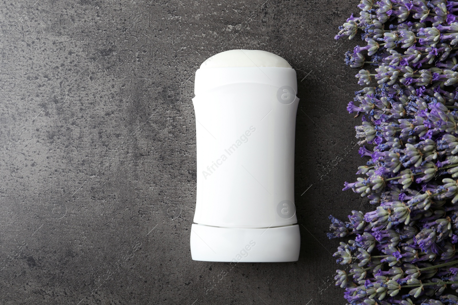 Photo of Female deodorant and lavender flowers on grey stone background, flat lay