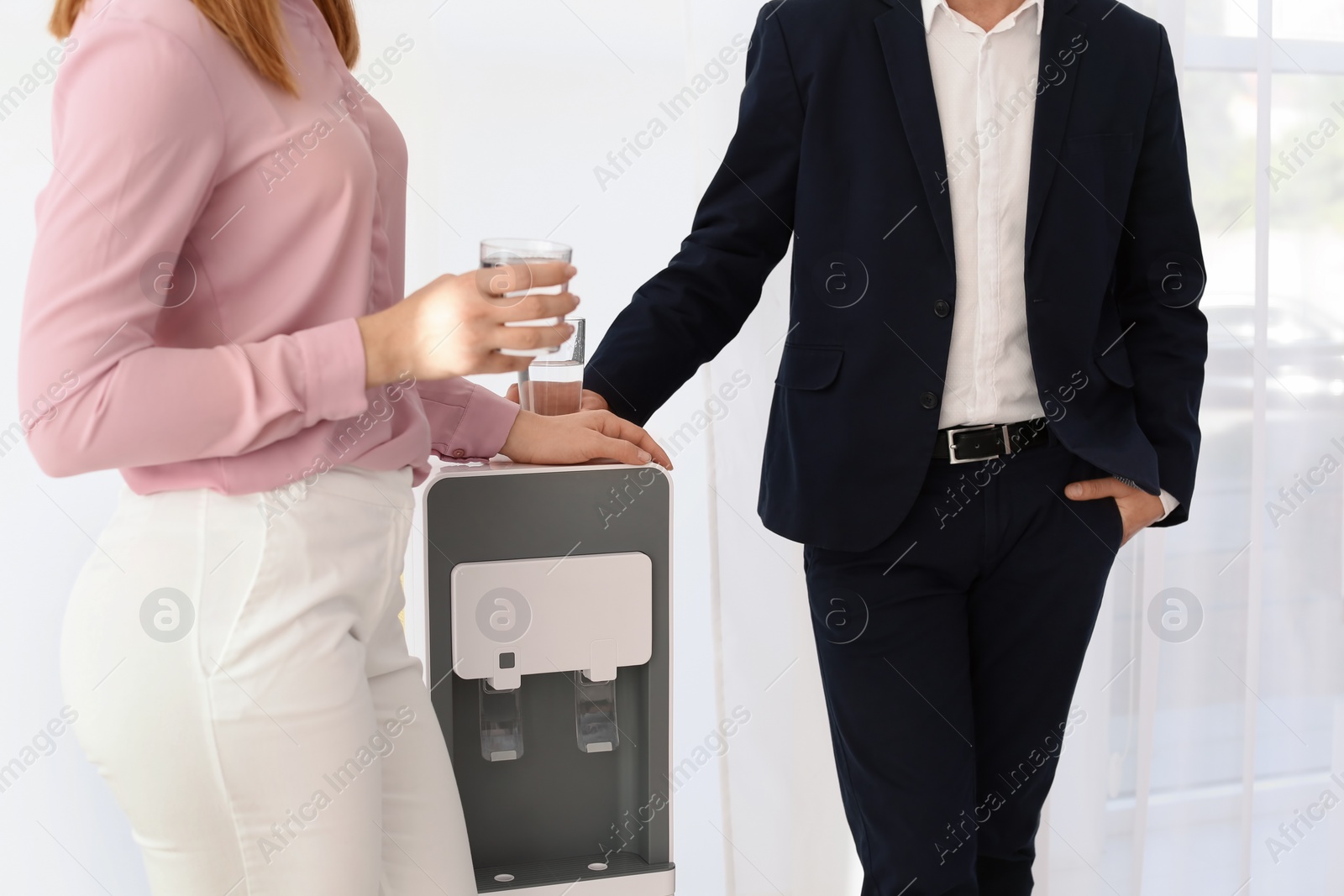 Photo of Co-workers having break near water cooler on white background, closeup