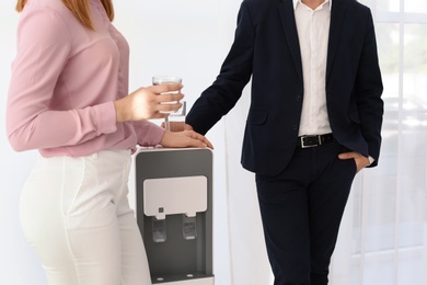 Photo of Co-workers having break near water cooler on white background, closeup