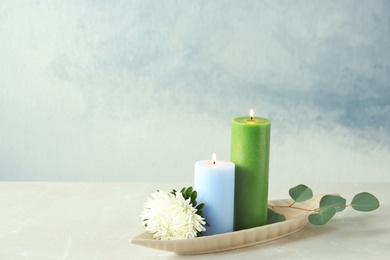 Photo of Candles with floral decor on table against color background