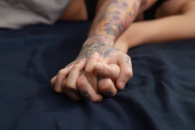 Photo of Passionate couple having sex on bed, closeup of hands