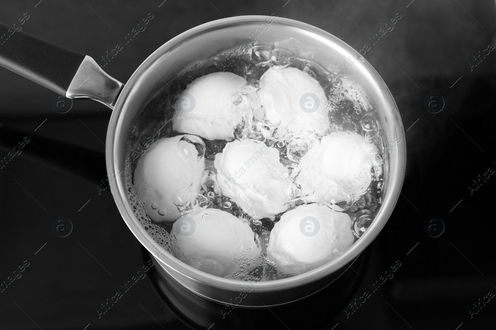 Photo of Chicken eggs boiling in saucepan on electric stove, above view