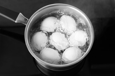 Photo of Chicken eggs boiling in saucepan on electric stove, above view