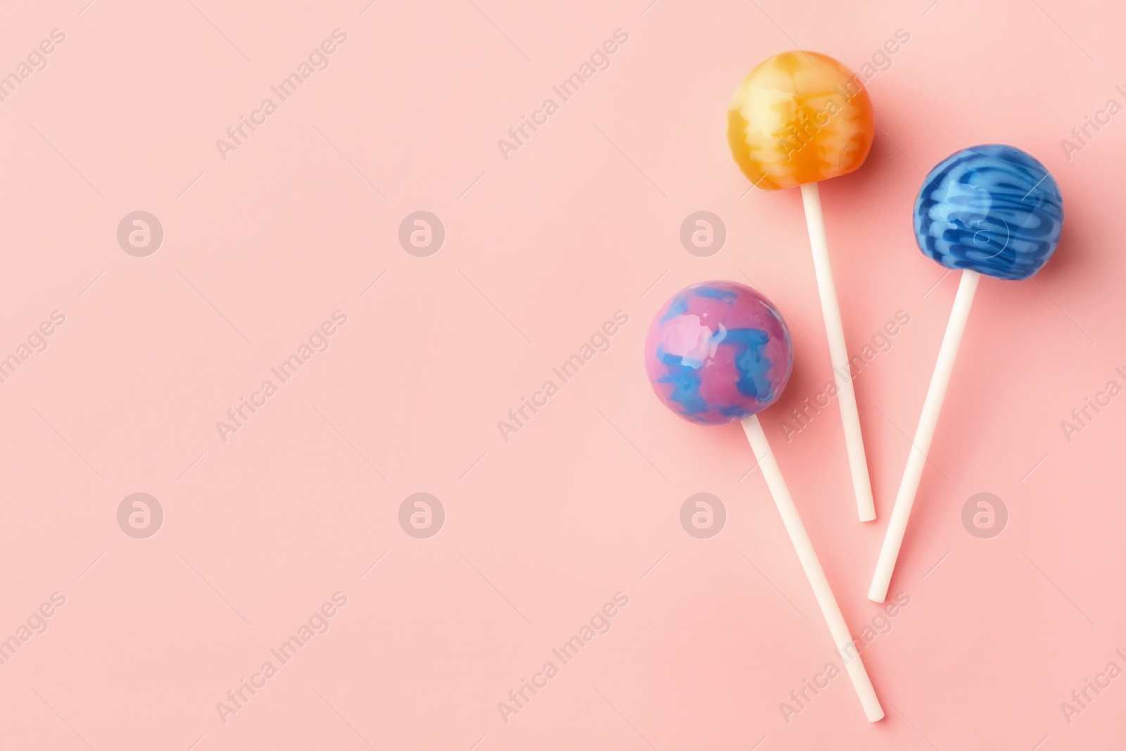 Photo of Tasty lollipops on pink background, flat lay. Space for text