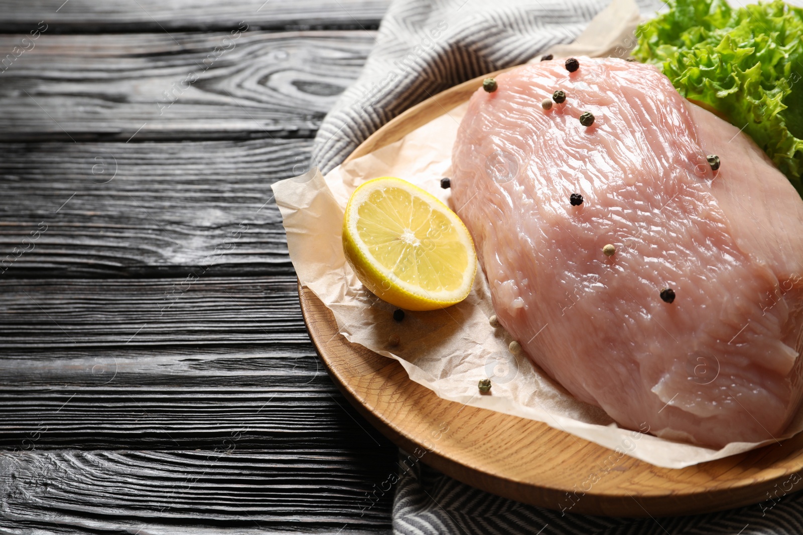 Photo of Plate with raw turkey fillet and ingredients on wooden background. Space for text