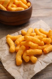 Many tasty cheesy corn puffs on wooden table