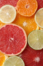 Photo of Slices of different citrus fruits as background, top view