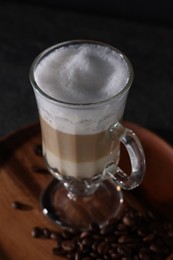 Photo of Aromatic latte macchiato in glass and coffee beans on table, closeup