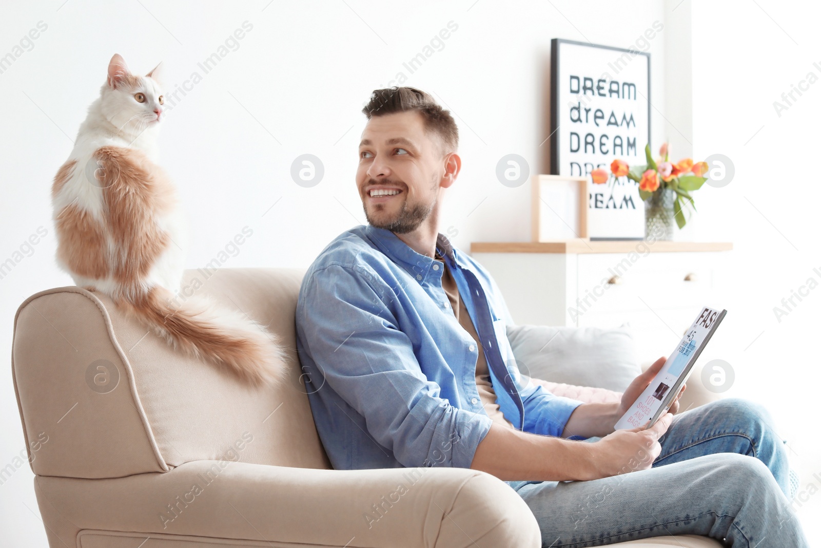 Photo of Young man with cute cat on sofa at home