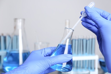 Photo of Doctor taking sample of blue liquid with dropper, closeup. Laboratory analysis