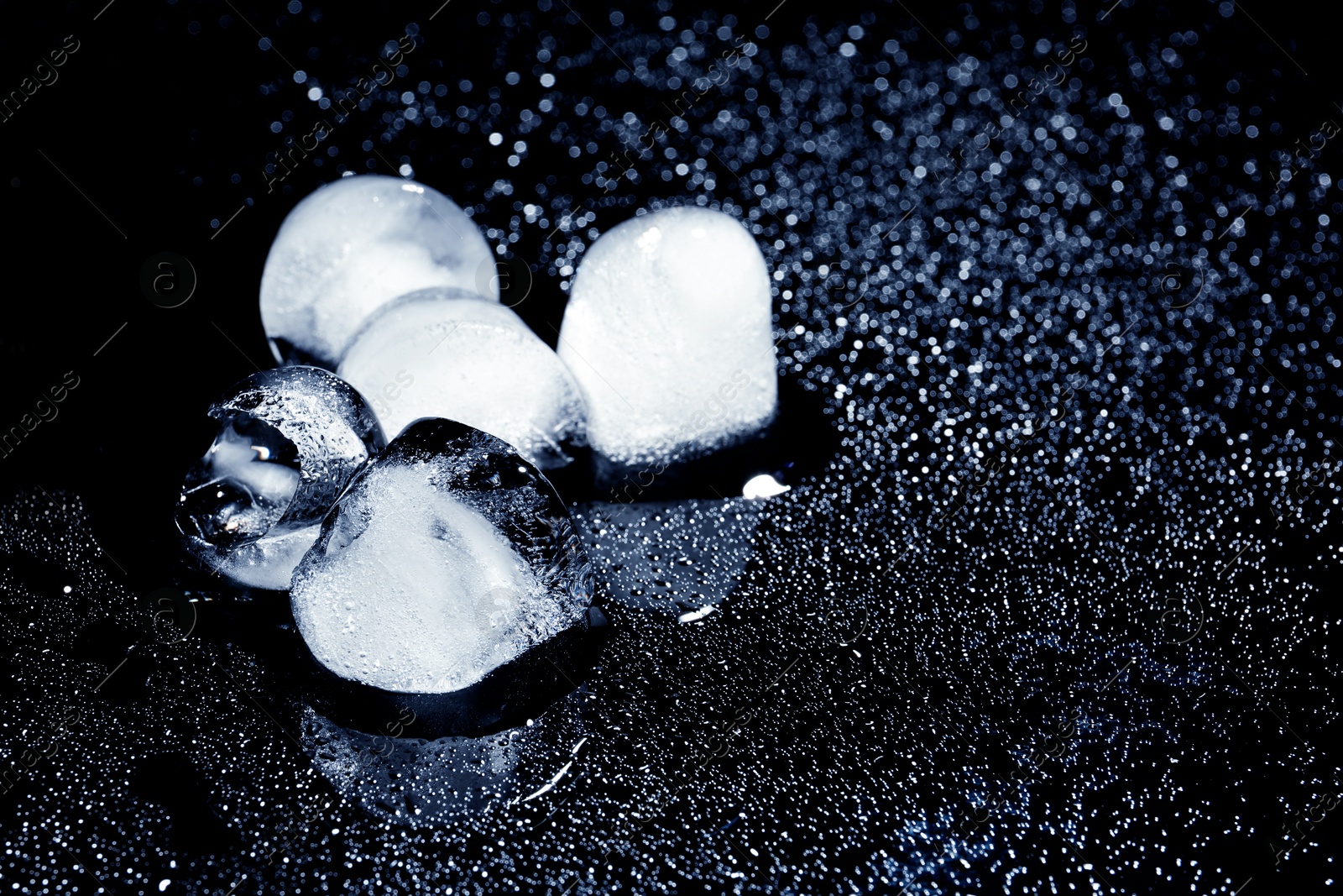 Photo of Melting ice cubes on black background. Space for text