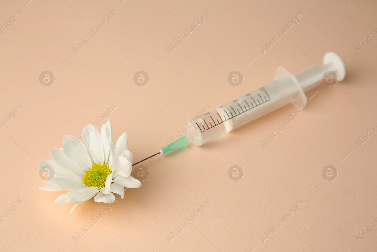 Medical syringe and beautiful chrysanthemum flower on beige background, closeup Photo of Medical syringe and beautiful chrysanthemum flower on beige background, closeup