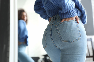 Woman wearing jeans near mirror indoors, closeup