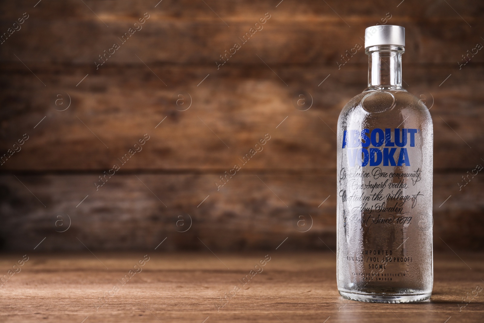 Photo of MYKOLAIV, UKRAINE - OCTOBER 04, 2019: Absolut vodka on table against wooden background. Space for text