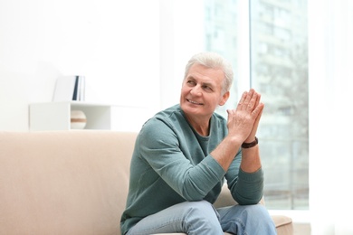 Portrait of handsome mature man on sofa indoors