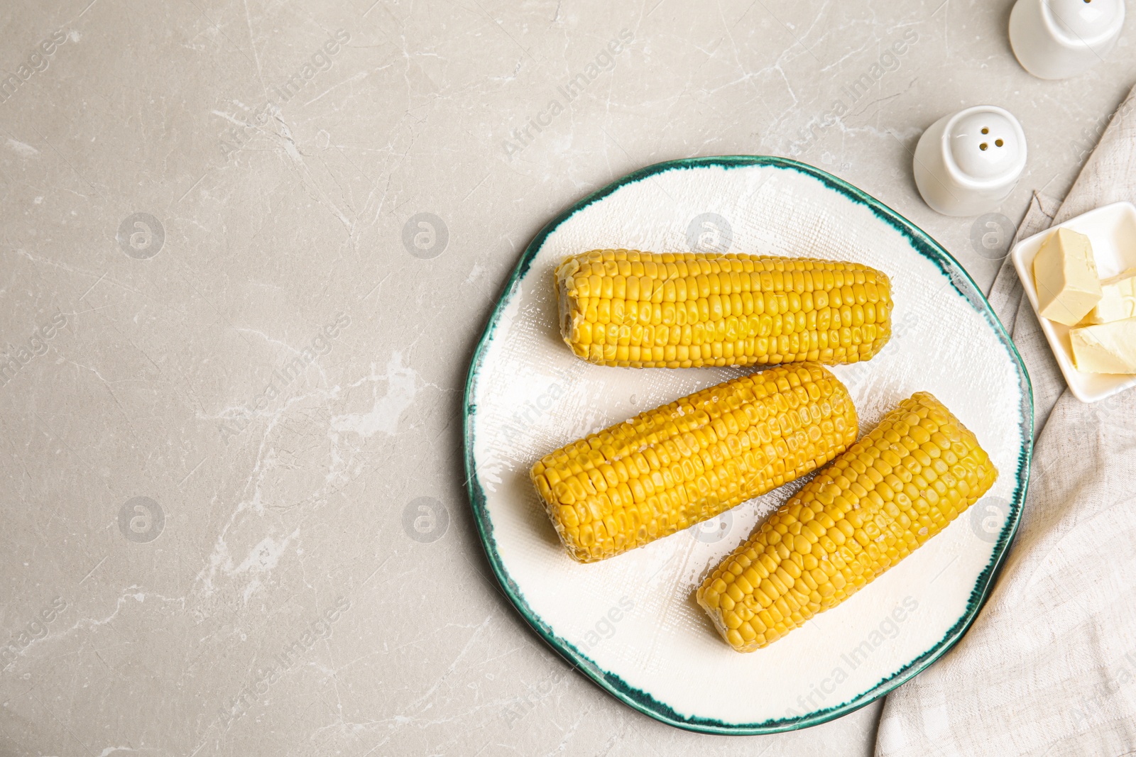 Photo of Delicious boiled corn served on light grey marble table, flat lay. Space for text