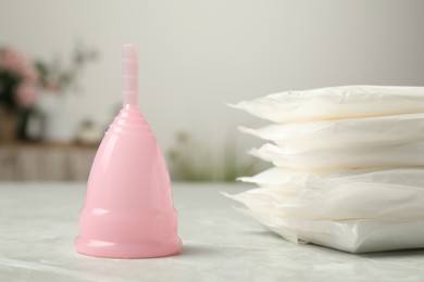 Photo of Menstrual cup and pads on grey table, closeup
