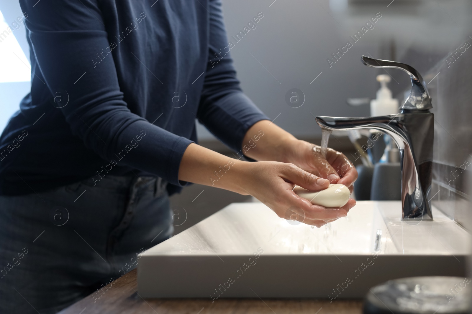 Photo of Woman with soap bar washing hands in bathroom, closeup