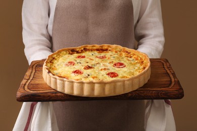 Photo of Woman with delicious homemade cheese quiche on beige background, closeup